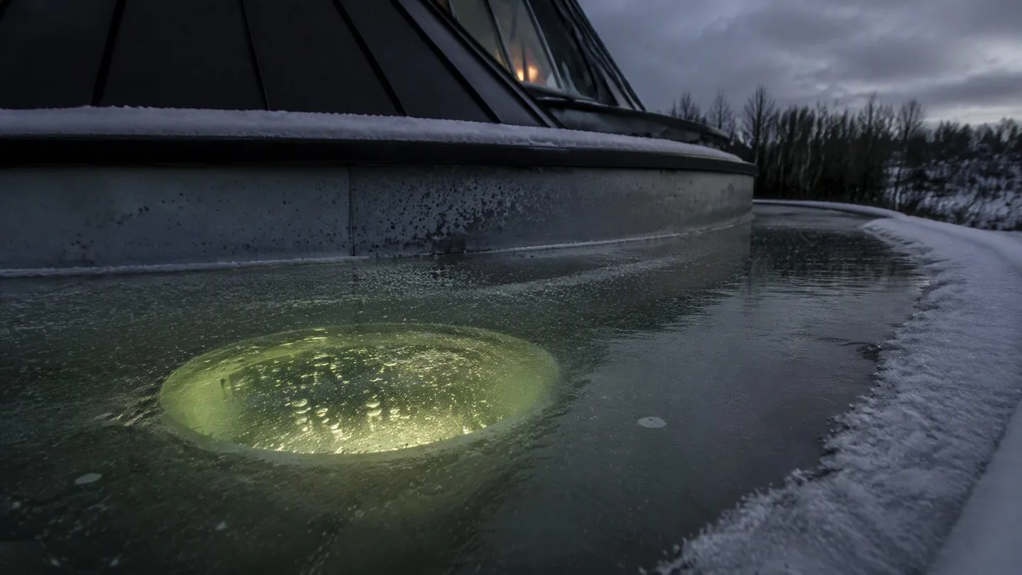 The round pond window glowing green-gold beneath a sheet of ice on the frozen moat